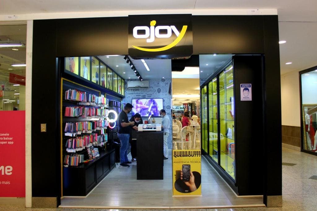 Fachada da loja no Itajaí Shopping, com a parede de capas coloridas à esquerda e o balcão de atendimento ao fundo